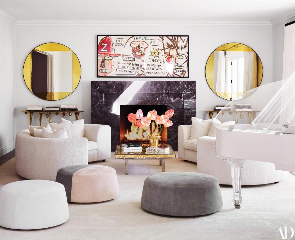 Mirrors by Wüd Furniture Design frame a Jean-Michel Basquiat screen print in the living room. On Yves Klein cocktail table, Tom Dixon gold vase; India Mahdavi sofas in Schumacher bouclé; custom suede poufs.