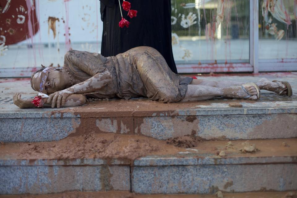 A woman covered in mud protests against Brazilian mining company Vale at the entrance of the company office, in Rio de Janeiro, Brazil, Monday, Jan. 28, 2019. There is mounting anger directed at Vale amid questions about the area's largest employer following an apparent lack of a warning siren ahead of Friday's collapse of a dam at one of its dams that has killed dozens. (AP Photo/Silvia Izquierdo)