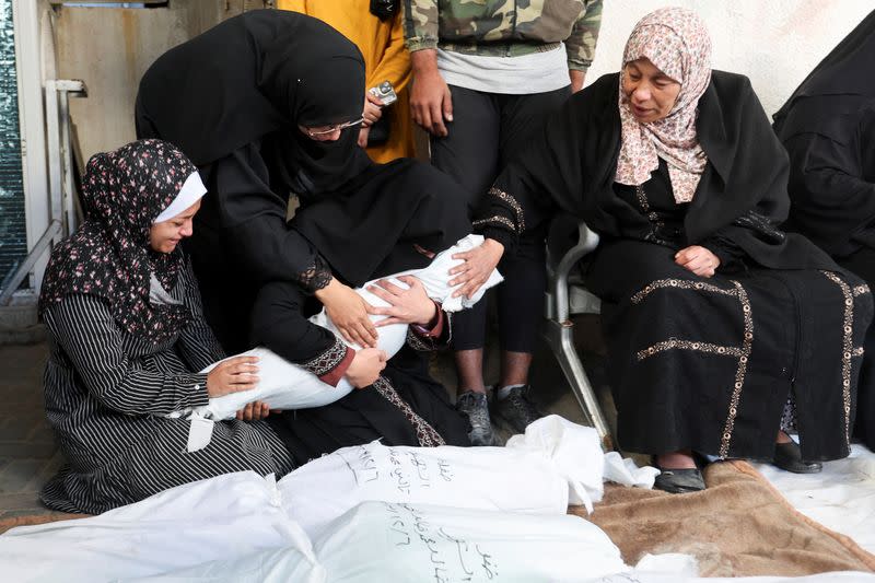Women mourn holding the body of a Palestinian killed in Israeli strikes on houses, at Abu Yousef al-Najjar hospital in Rafah