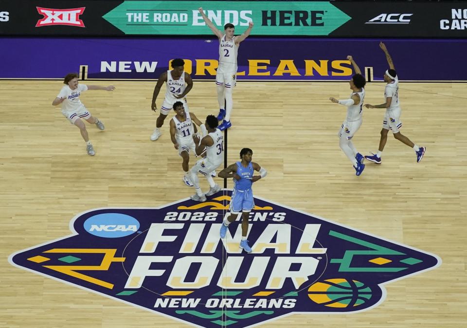 FILE - Kansas players celebrate a win over North Carolina after a college basketball game in the finals of the men's Final Four NCAA tournament, Monday, April 4, 2022, in New Orleans. College football and men's basketball players on scholarship in one of the major conferences can expect to soon earn a minimum of $50,000 each year he plays because of the influx of cash from so-called booster collectives brokering name, image and likeness deals. That prediction, based on market trends, was made this week by Blake Lawrence, co-founder and CEO of a company that helps athletes and schools navigate the ever-changing NIL landscape. (AP Photo/David J. Phillip, File)