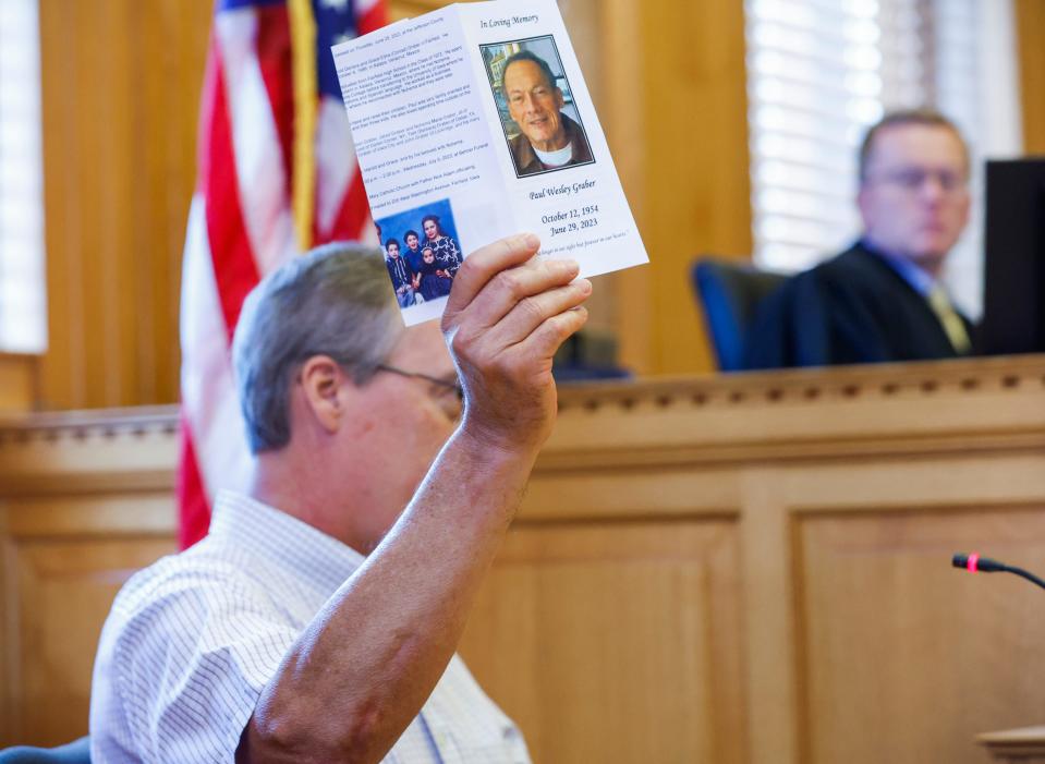 Jim Graber, a brother-in-law of murdered Spanish teacher Nohema Graber, raises the funeral program for his brother Paul, her ex-husband, as he makes a victim impact statement during the sentencing of Willard Miller at the Jefferson County Courthouse in Fairfield on Thursday. Graber's relatives made clear they hold Miller responsible for both deaths.