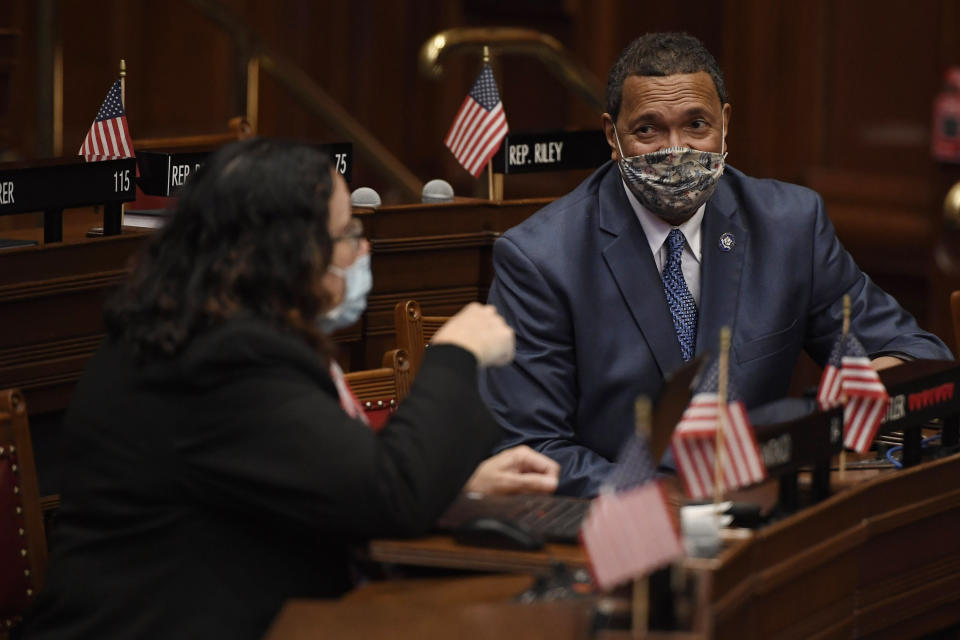 State Rep. Hilda Santiago, D-Meriden, left, talks with Rep. Larry Butler, D-Waterbury, right, during session at the State Capitol in Hartford, Conn., on Monday, April 19, 2021. In July 2020 after George Floyd was killed in Minneapolis, Black and Latino members of the Connecticut General Assembly worked to enact sweeping changes to policing in the state, and since, have continue to flex their collective muscles. (AP Photo/Jessica Hill)