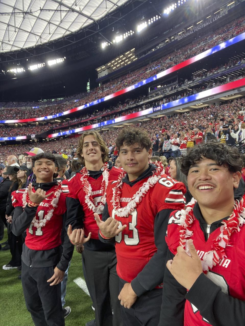 In this Feb. 11, 2024, image provided by Jonathan Conrad, athletic director at Lahainaluna High School, members of the Lahainaluna High School football team flash the "shaka" hand gesture as they pose for a photo while attending the NFL Super Bowl 58 football game in Las Vegas. (Jonathan Conrad via AP)