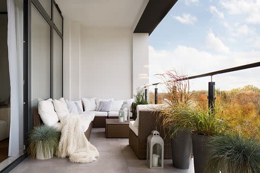 elegant decorated balcony with rattan outdoor furniture, bright pillows and plants