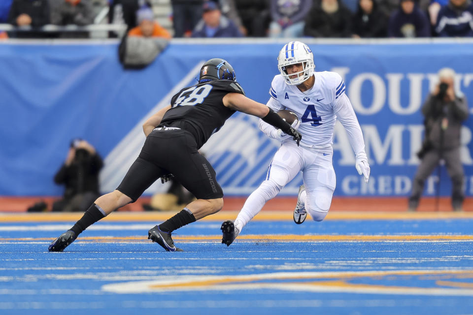 BYU running back Lopini Katoa (4) cuts back with the ball while trying to avoid a tackle-attempt by Boise State linebacker Ty Tanner (58) in the first half of an NCAA college football game, Saturday, Nov. 5, 2022, in Boise, Idaho. (AP Photo/Steve Conner)