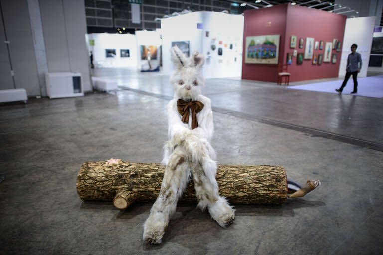 A man (top R) walks down an alley of the Art Basel Hong Kong fair past an artwork by Marnie Weber titled "Log Lady and Dirty Bunny" (C), May 22, 2013. The first Art Basel fair to be hosted by Hong Kong boasts a prestigious array of international art, highlighting the city's new role as a global arts hub amid an explosion of personal wealth in mainland China