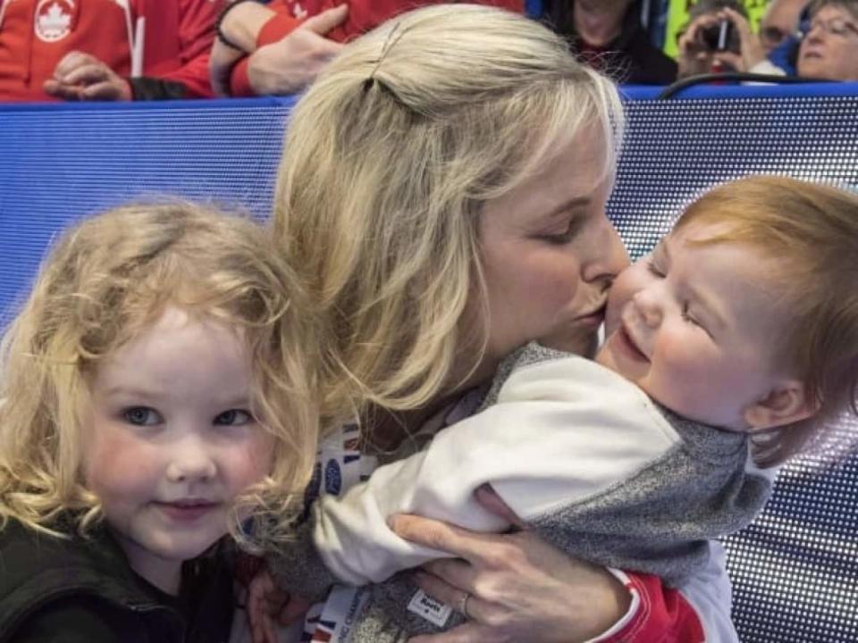 Canadian curling skip Jennifer Jones, seen above in a file photo from 2018, embraces her children Isabella, left, and Skyla. (Paul Chiasson/The Canadian Press - image credit)