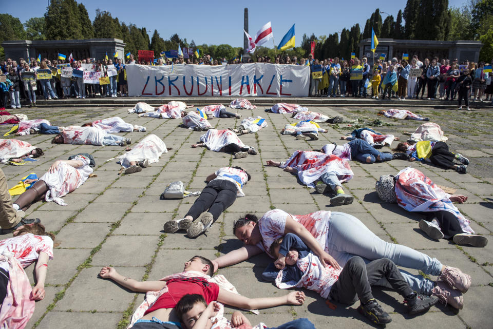 People lie on the ground as they symbolize the civilian victims of the war in Ukraine to protest Sergey Andreev's visit.