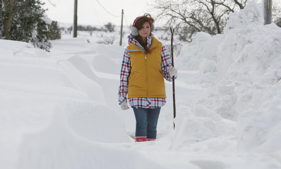 Cara Faith, 21, uses a stick to walk on the main road to Feystown, above Glenarm in Co Antrim. Glenarm, a hill town hamlet, has been cut off from electricity for three days. Heavy snow and blizzard conditions brought down power lines and the continuing hazardous weather have prevented emergency workers from restoring electricity (PA)