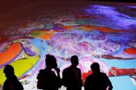 Visitors are seen in front of a painting by the British artist Sacha Jafri at the Atlantis hotel in Dubai