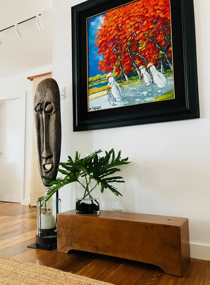 Wooden bench under painting in art filled apartment.