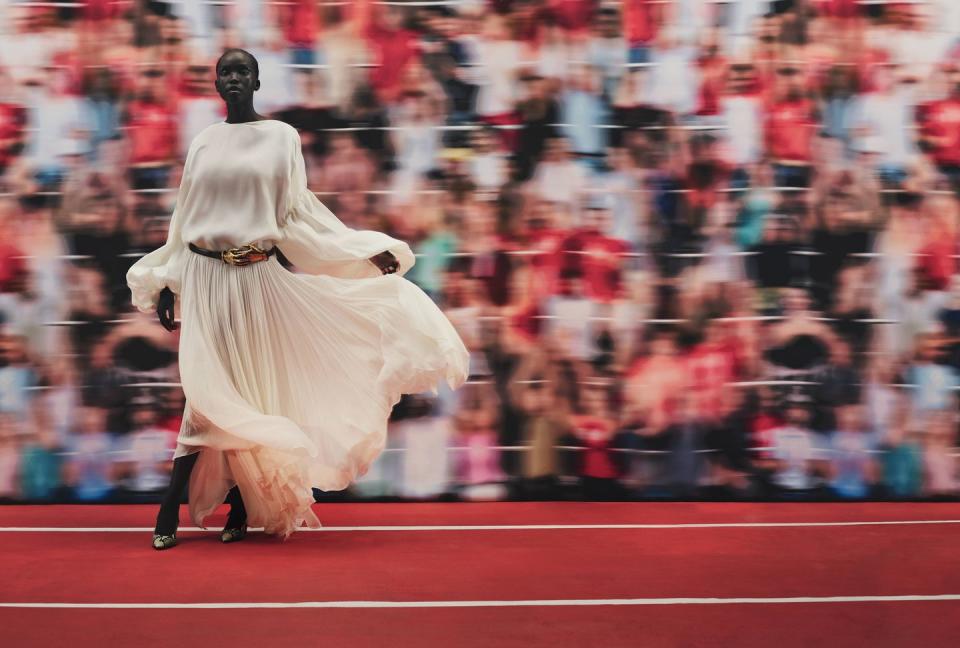 a person in a white dress running on a track with a crowd watching