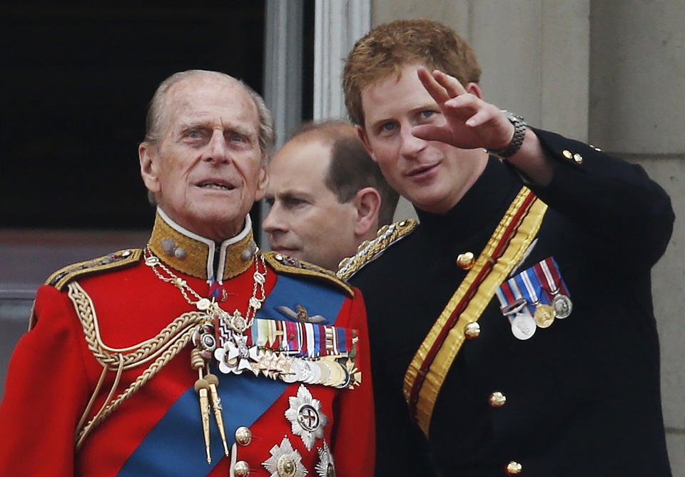 FILE - In this June 14, 2014 file photo, Britain's Prince Harry talks to Prince Philip, left, as members of the Royal family appear on the balcony of Buckingham Palace, during the Trooping The Colour parade, in central London. In the TV program ‘Prince Philip: The Royal Family Remembers’ released late Saturday Sept. 18, 2021, members of the royal family spoke admiringly of the late Duke of Edinburgh’s barbecuing skills and Prince Harry described how his grandfather would “never probe” but listen intently about his two tour of duties to Helmand province during the war in Afghanistan. (AP Photo/Lefteris Pitarakis, File)