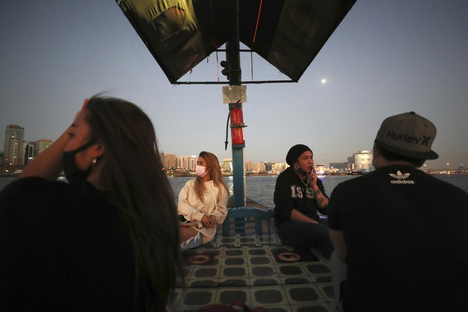 From left to right, April Joy, vocalist, Catherine Gallano, dancer and lead choreographer and Eric Roman, vocalist, cross the creek on a boat in Dubai, United Arab Emirates, Wednesday, Oct. 28, 2020. As the coronavirus pandemic mutes Dubai's live-music scene, the Filipino show bands that long have animated the city's storied nightlife are being disproportionately squeezed. Many are out of work and out of money, struggling to survive in overcrowded dormitories at the mercy of employers (AP Photo/Kamran Jebreili)