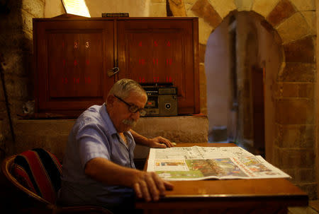 Palestinian Saleem Al-Wazeer, owner of As-Samra bath house, reads a newspaper in Gaza City. REUTERS/Suhaib Salem