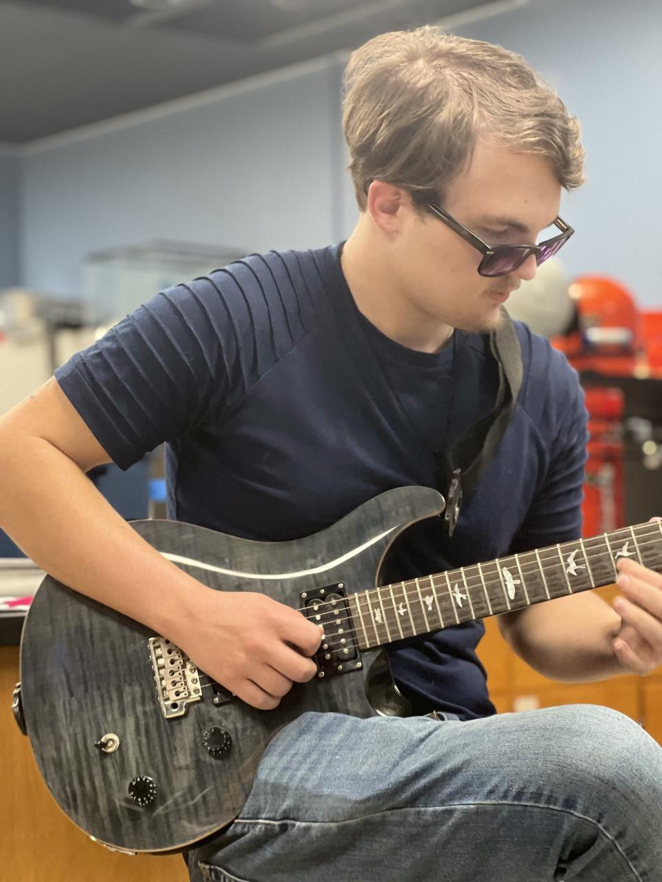 Levi Heisinger playing his guitar, an item that he said soothes him when he's feeling overwhelmed at any given time. Heisinger is an employee at the New Mexico National Space Museum where he first started as an intern in 2023.