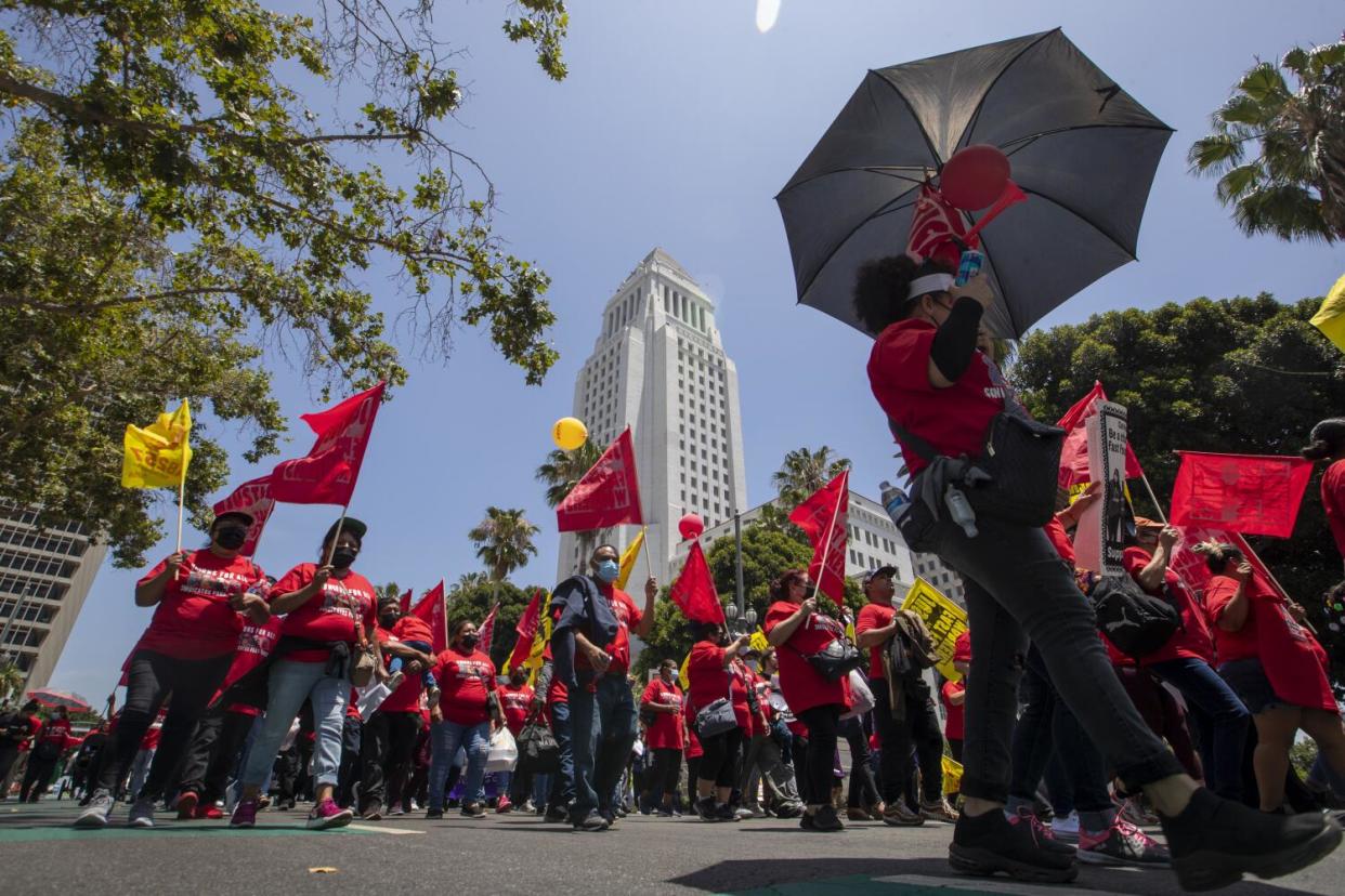 People with red and yellow flags gather in front of Los Angeles City Hall.