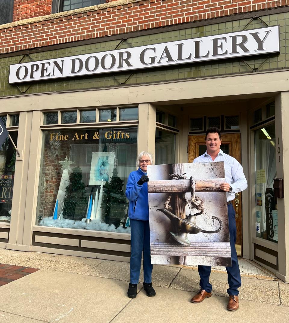 Bev Benne, director of the Open Door Gallery, and Ryan Conrod, DDA events coordinator, show off a piece of art that will be on display during the downtown Sturgis Winter Wine Down and Art About Town events Friday.