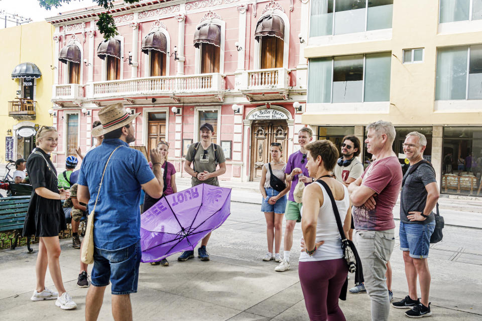 Tour guide talking to a group of tourists standing in a city square