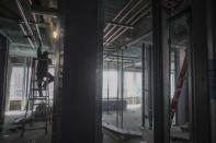 A construction worker climbs a ladder to assemble pipes on the 28th floor of a high rise at 160 Water Street in Manhattan's financial district, undergoing conversion to residential apartments, Tuesday, April 11, 2023, in New York. (AP Photo/Bebeto Matthews)