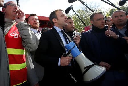 Emmanuel Macron (C), head of the political movement En Marche !, or Onwards !, and candidate for the 2017 French presidential election, uses a megaphone to talk to Whirlpool employees in front of the company plant in Amiens, France, April 26, 2017. REUTERS/Pascal Rossignol