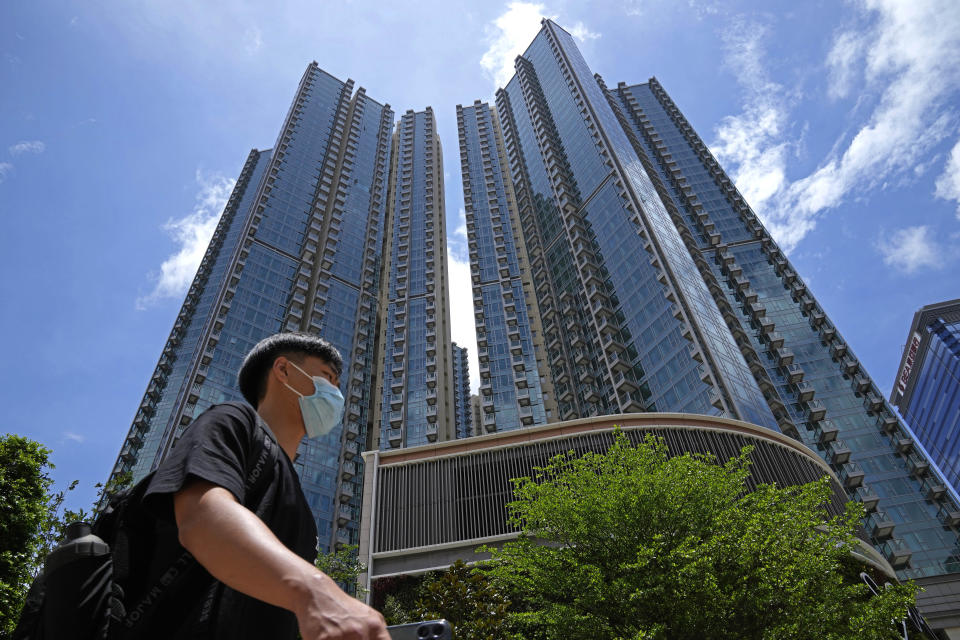 In this Tuesday, June 15, 2021, photo, a man walks in front of the Grand Central residential building complex where one of the HK$10.8 million (US$1.4 million) 449 square feet single-room flats will be offered as a prize in a lucky draw. Coronavirus vaccine incentives offered by Hong Kong companies, including a lucky draw for an apartment, a Tesla car and even gold bars, are helping boost the city’s sluggish inoculation rate. (AP Photo/Kin Cheung)