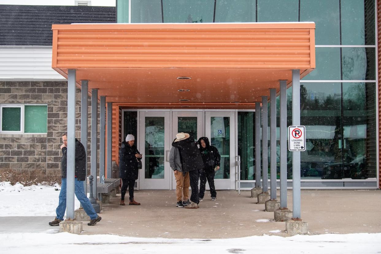 People comfort each other outside the Kerry Vickar Centre in Melfort, Sask., on Tuesday during a lunch break at the public coroner's inquest into the mass stabbings that happened on James Smith Cree Nation in 2022. (Liam Richards/The Canadian Press - image credit)