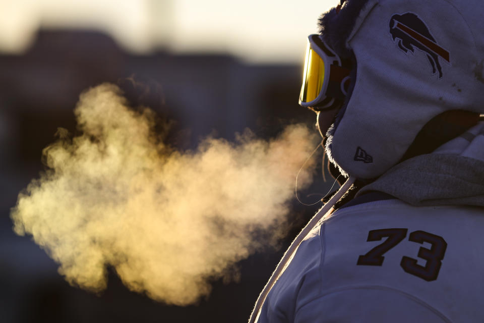 A tailgating fan exhales a cloud of vapor as temperatures drop in the parking lots outside of Highmark Stadium before an NFL wild-card playoff football game between the Buffalo Bills and the New England Patriots, Saturday, Jan. 15, 2022, in Orchard Park, N.Y. (AP Photo/Joshua Bessex)
