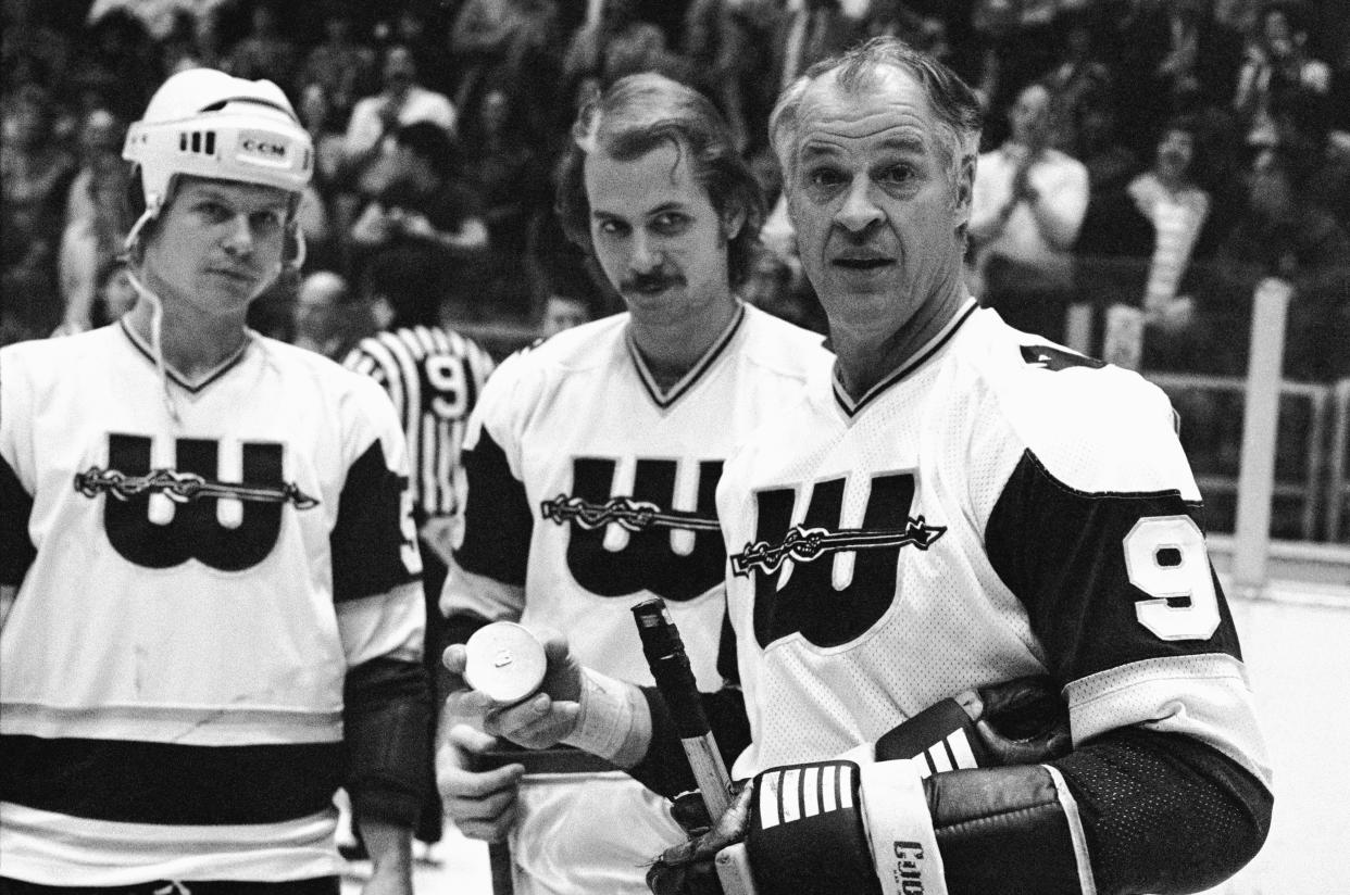 (Original Caption) A little fatherly advice as hockey great Gordie Howe accepts a gold puck from his sons and teammates Mark and Marty Howe (c) in recognition of his 1,000th goal. The presentation was made before the Whalers game in Hartford, 12/14, against the Soviet All-Stars.