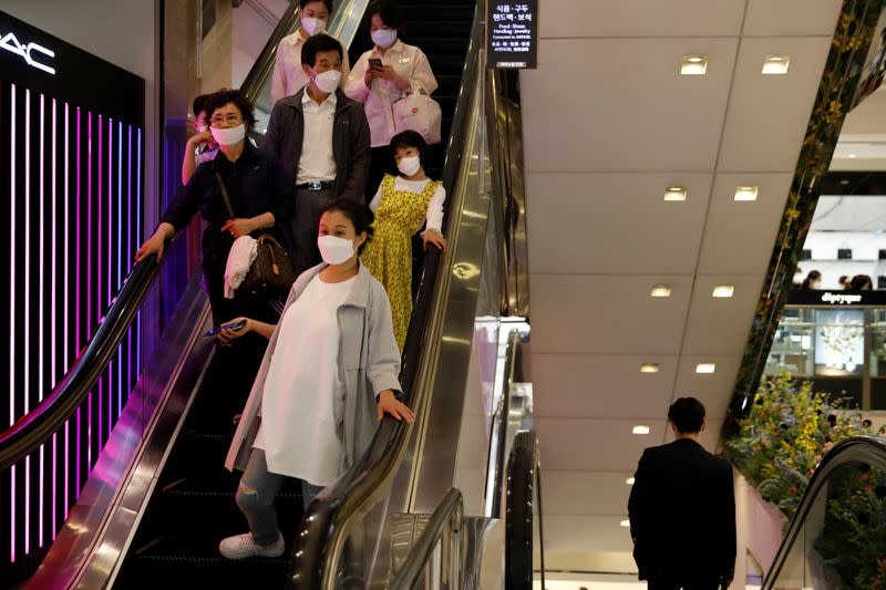 People wearing masks to avoid the spread of the coronavirus disease (COVID-19) ride on an escalator at a department store in Seoul