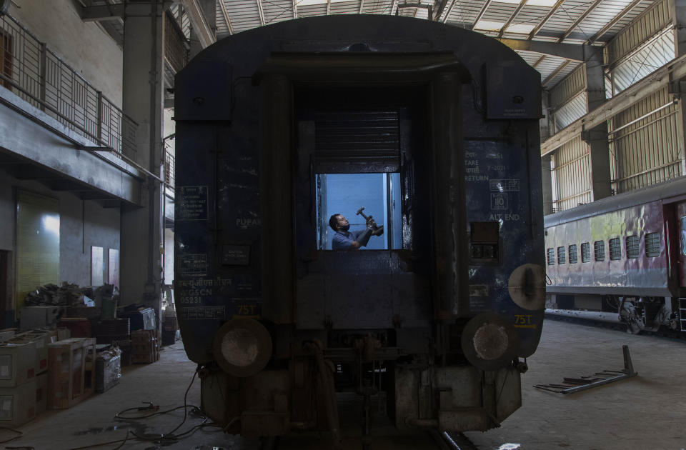 An Indian railway employee works to convert a train coach into an isolation ward for the fight against the new coronavirus in Gauhati, India, Sunday, March 29, 2020. Indian Prime Minister Narendra Modi apologized to the public on Sunday for imposing a three-week national lockdown, calling it harsh but "needed to win" the battle against the coronavirus pandemic. The new coronavirus causes mild or moderate symptoms for most people, but for some, especially older adults and people with existing health problems, it can cause more severe illness or death. (AP Photo/Anupam Nath)