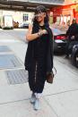 <p>In a black cape and dress with a Louis Vuitton bag, grey sneakers, and her Dior sunglasses collaboration designs </p>
