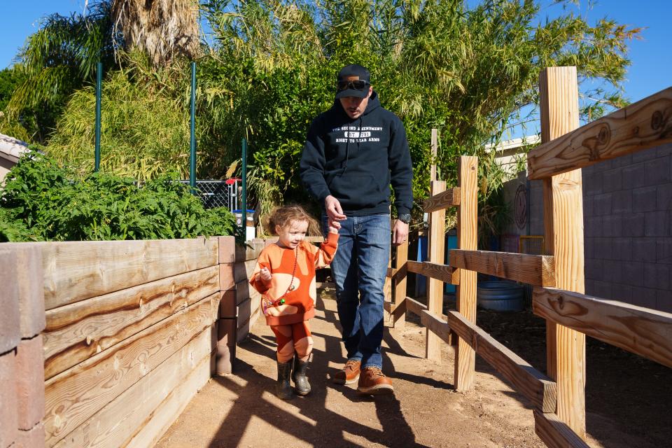 Dereck Nielsen, takes daughter, Pearl Nielsen to see the pigs at Blue Rooster Produce on Nov. 19, 2022 in Peoria, AZ.