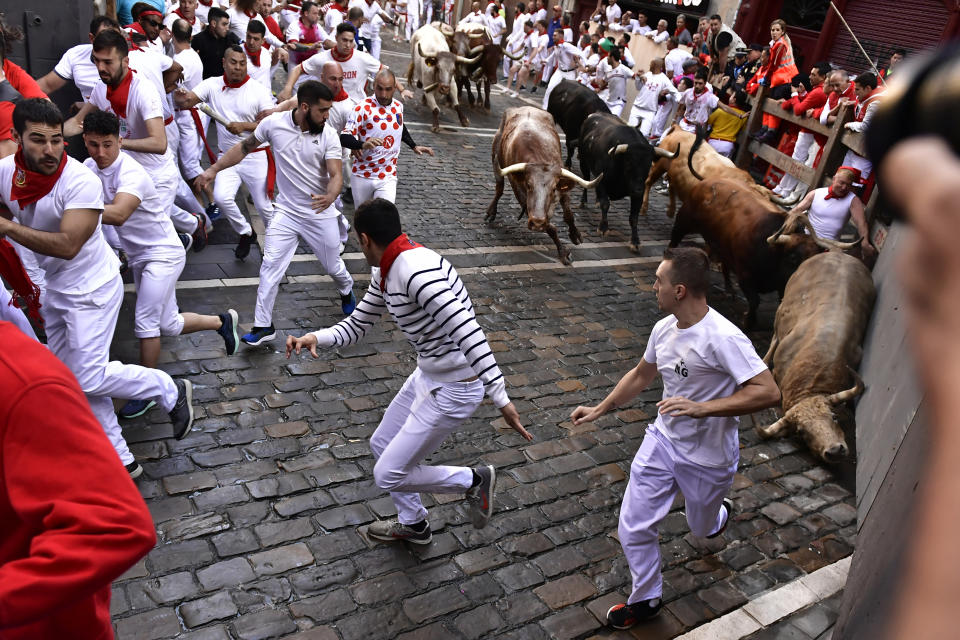 People run through the streets with fighting bulls and steers during the first day of the running of the bulls at the San Fermin Festival in Pamplona, northern Spain, Thursday, July 7, 2022. Revellers from around the world flock to Pamplona every year for nine days of uninterrupted partying in Pamplona's famed running of the bulls festival which was suspended for the past two years because of the coronavirus pandemic. (AP Photo/Alvaro Barrientos)