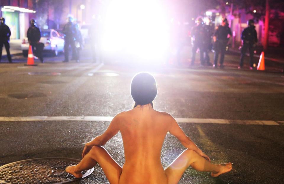 A naked woman confronts federal officers in Portland on Friday.