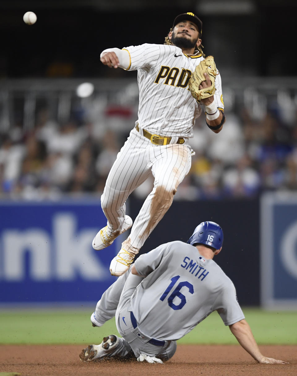 San Diego Padres shortstop Fernando Tatis Jr. (23) throws over Will Smith (16) as he tries to turn a double play during the fourth inning of a baseball game Wednesday, June 23, 2021, in San Diego. Tatis was unable to turn the double and was charged with a throwing error. (AP Photo/Denis Poroy)