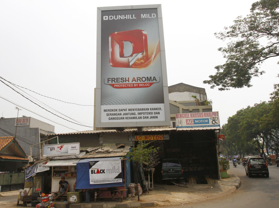 A man sits near a billboard advertising cigarettes by a busy street in Jakarta, Indonesia, Tuesday, Sept. 11, 2012. Indonesian men rank as the world’s top smokers, with two out of three of them lighting up in a country where cigarettes cost pennies and tobacco advertising is everywhere. (AP Photo/Achmad Ibrahim)