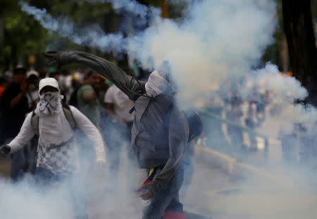 A demonstrator throws a tear gas canister back to police during clashes while rallying against Venezuela's President Nicolas Maduro in Caracas, Venezuela, April 20, 2017. REUTERS/Marco Bello