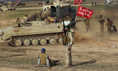 Shi'ite fighters sit in front of a tank during deployments in the town of Hamrin in Salahuddin province March 3, 2015. REUTERS/Thaier Al-Sudani