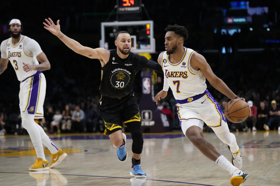 Los Angeles Lakers' Troy Brown Jr. (7) drives past Golden State Warriors' Stephen Curry (30) during the first half of an NBA basketball game Sunday, March 5, 2023, in Los Angeles. (AP Photo/Jae C. Hong)