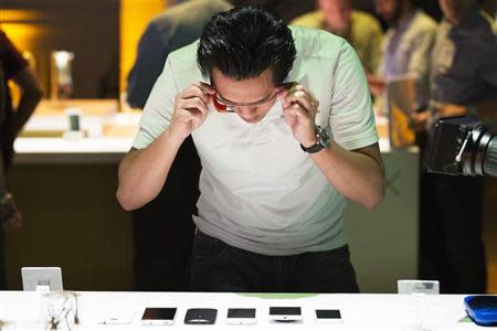 A man uses Google Glass to photograph examples of Motorola's new Moto X phone next to other mobile phones at a launch event in New York, August 1, 2013. REUTERS/Lucas Jackson