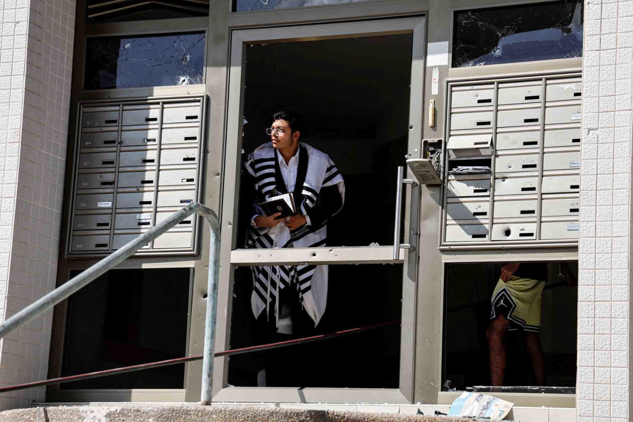 Image: A man in Ashkelon looks out of a damaged building entryway. (Ammar Awad / Reuters)