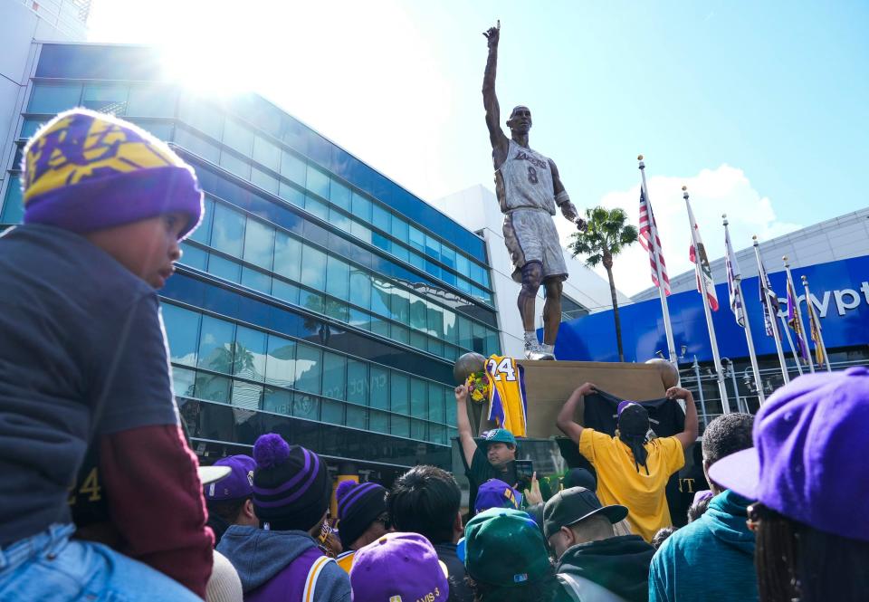 Los Angeles Lakers fans gather around a statue honoring Hall of Famer Kobe Bryant at Crypto.com Arena on Feb. 9, 2024. Bryant won five NBA championships and played all 20 of his NBA seasons with the franchise. Bryant died in a helicopter crash with his daughter Gianna in January 2020. The statue of Bryant was unveiled to the public today after a private event the day before.