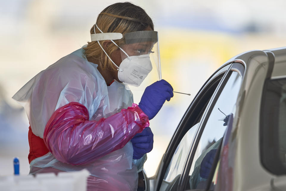 A nurse in protective gear administers a coronavirus test in Omaha, Neb., Wednesday, July 8, 2020. Vice President Mike Pence says the U.S. government will issue guidance encouraging front-line health care workers to reuse personal protective equipment. Pence added that PPE supplies remain "very strong" but the Trump administration will be encouraging healthcare workers "to use some of the best practices" to "preserve and reuse" face masks and other protective equipment. (AP Photo/Nati Harnik)