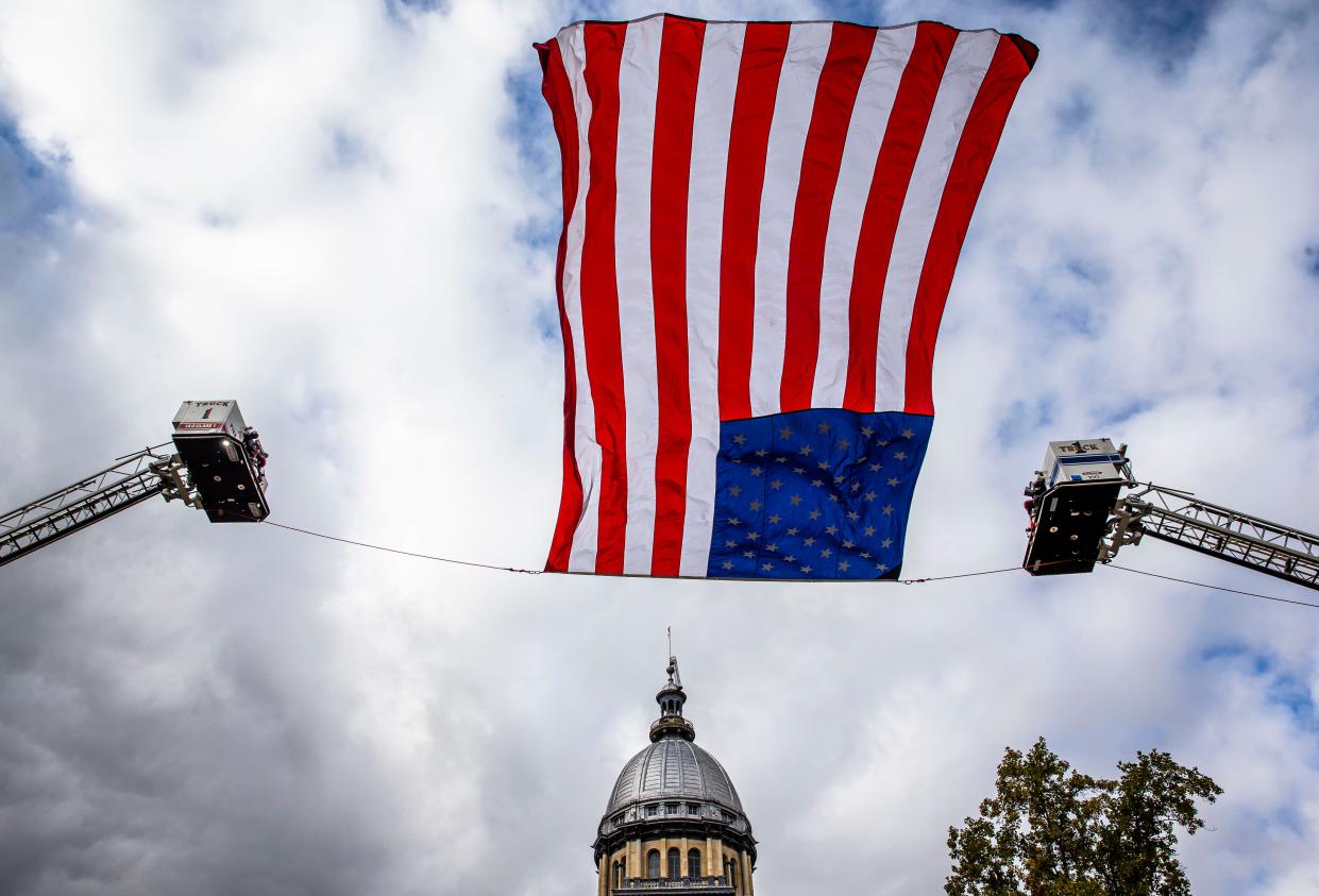 A giant American flag from the Springfield Fire Department flies over Capitol Avenue in front of the Illinois Capitol Building.