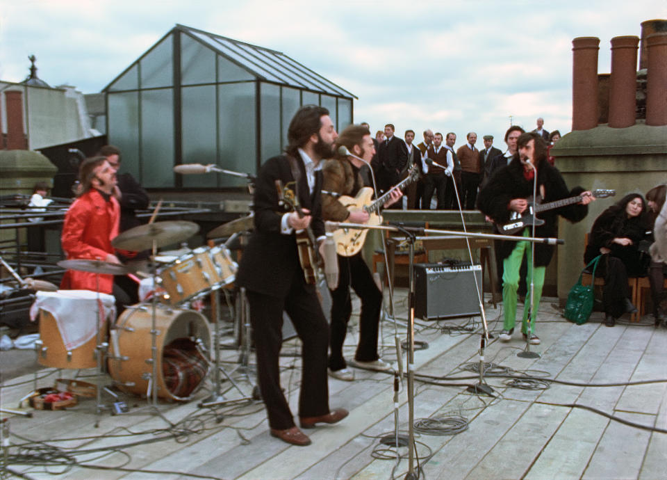 This image released by Disney+ shows, from left, Ringo Starr, Paul McCartney, John Lennon and George Harrison, with Yoko Ono, seated right, in a scene from the nearly 8-hour Peter Jackson-produced documentary “Get Back,” airing over three days starting Thanksgiving. (Disney+ via AP)