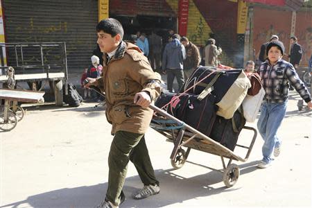 A boy pulls a trolley containing belongings at the Karaj al-Hajez crossing, a passageway separating Aleppo's Bustan al-Qasr, which is under the rebels' control and Al-Masharqa neighbourhood, an area controlled by the regime February 9, 2014. REUTERS/Hosam Katan