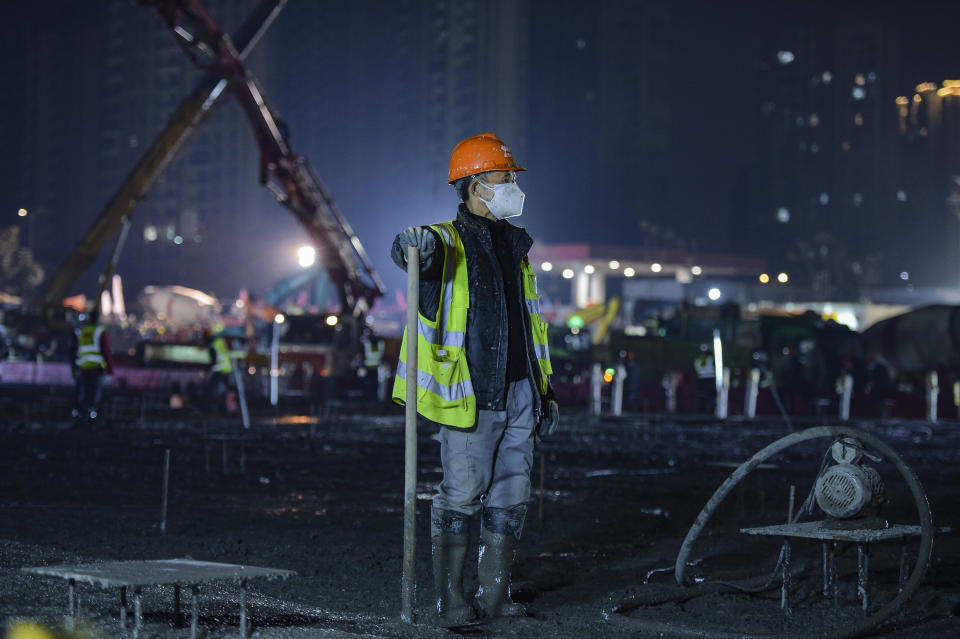 In this Tuesday, Jan. 28, 2020 photo, a construction worker rests at the site of the Huoshenshan temporary field hospital being built in Wuhan in central China's Hubei Province. China as of Wednesday has more infections of a new virus than it did in with SARS, though the death toll is still lower. (Chinatopix via AP)