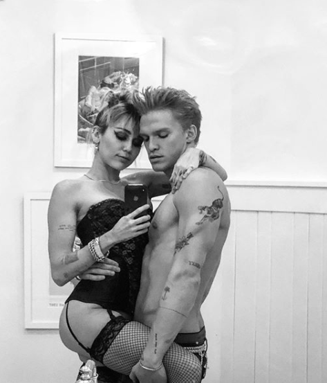 Miley Cyrus wears black lingerie while embracing her boyfriend Cody Simpson who is shirtless