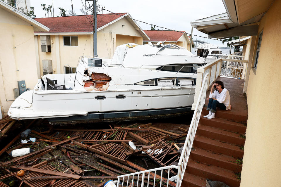 Brenda Brennan sits next to a boat that was pushed against her apartment by Hurricane Ian in Fort Myers on Sept. 29, 2022.